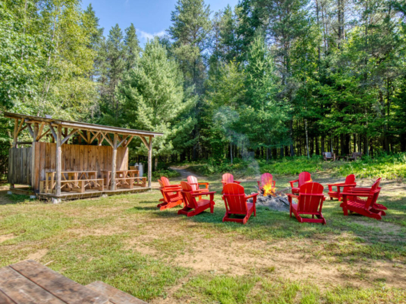 Espace commun de feu de camp avec chaises et abri. Un site de camping à vendre dans les Laurentides, près de Mont-Tremblant