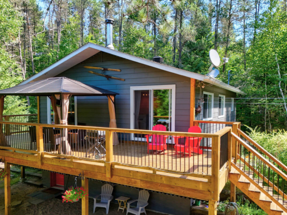 Maison de propriétaire de camping à vendre dans les Laurentides, près de Mont-Tremblant. Grande terrasse en bois et arbres matures