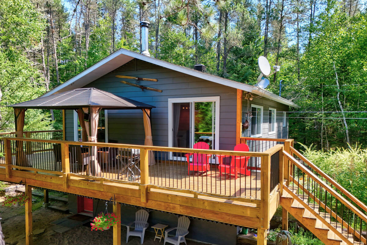 Maison de propriétaire de camping à vendre dans les Laurentides, près de Mont-Tremblant. Grande terrasse en bois et arbres matures