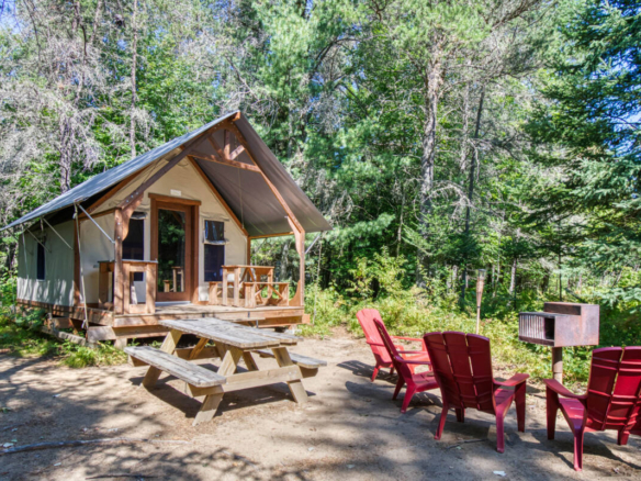Tente de glamping avec terrasse en bois, chaises et barbecue sur un site de camping à vendre dans les Laurentides, près de Mont-Tremblant