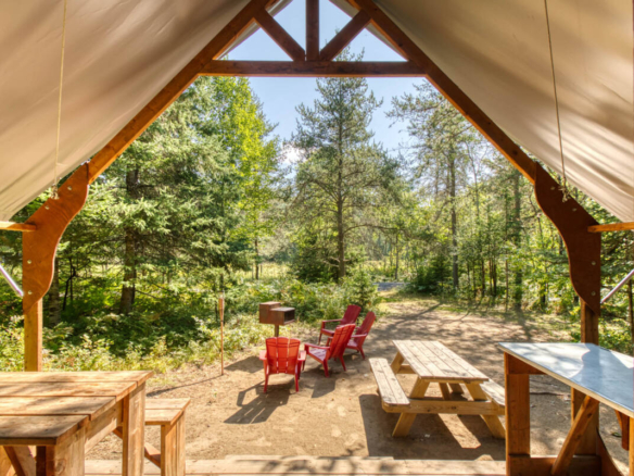 Intérieur d'une tente prospecteur de glamping sur un site de camping à vendre dans les Laurentides, près de Mont-Tremblant, avec table de pique-nique et chaises