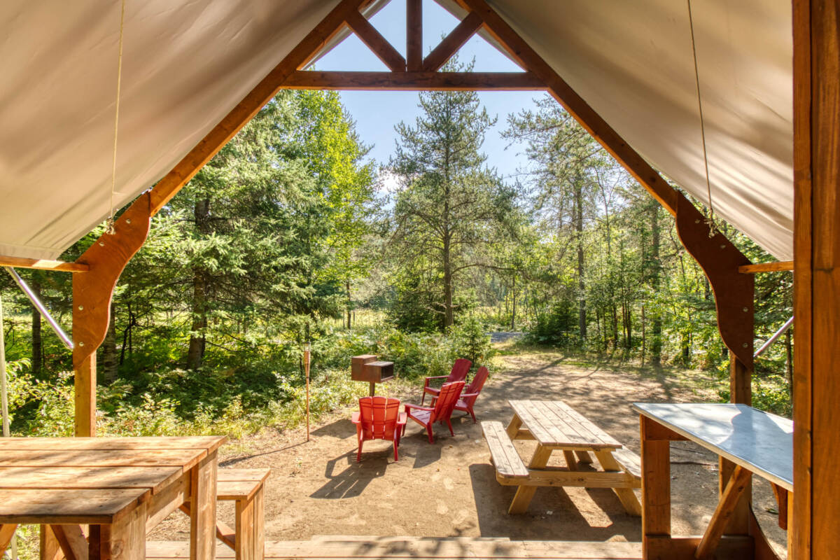 Intérieur d'une tente prospecteur de glamping sur un site de camping à vendre dans les Laurentides, près de Mont-Tremblant, avec table de pique-nique et chaises