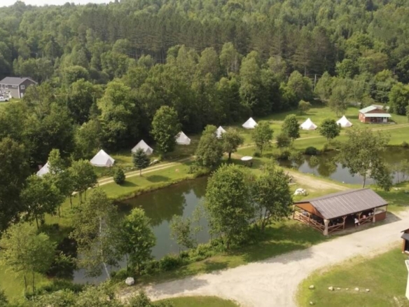 Vue aérienne d'un domaine de glamping à vendre et centre de ressourcement avec étang privé à vendre près de Mont-Tremblant.