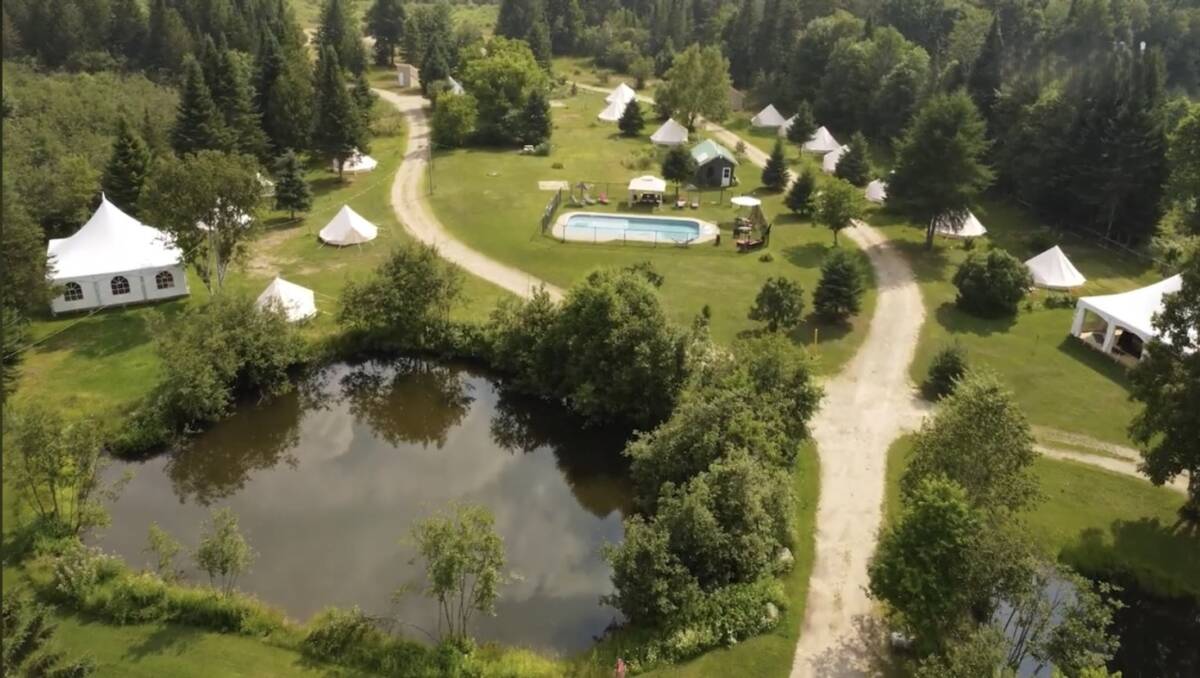 Aérienne #Domaine Glamping avec Piscine à Vendre – Mont-Tremblant Texte alternatif : Vue aérienne d'un domaine de glamping à vendre avec piscine, étang et tentes aménagées près de Mont-Tremblant.