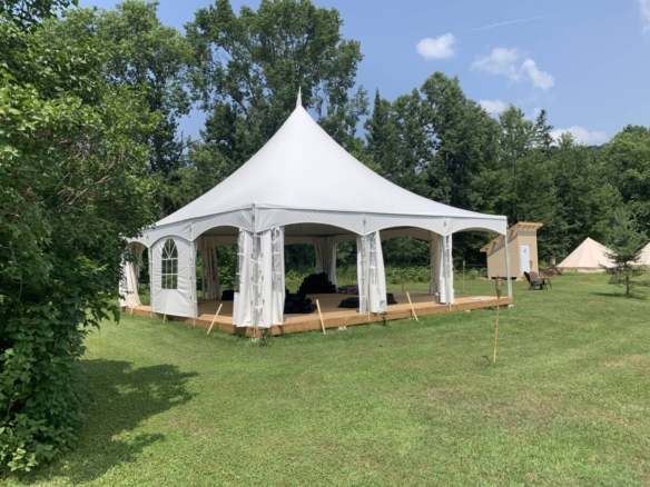 Grand chapiteau blanc sur plateforme en bois aménagé pour le yoga sur un domaine de glamping à vendre près de Mont-Tremblant.