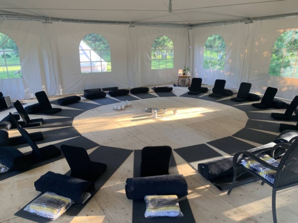 Intérieur d'un chapiteau aménagé avec des tapis de yoga en cercle pour des retraites sur le domaine à vendre.