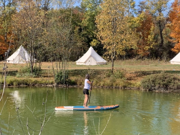 Femme faisant de la planche à pagaie sur l'étang du domaine de glamping à vendre près de Mont-Tremblant.