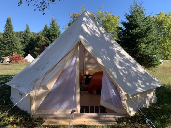 Extérieur d'une tente de glamping de style prospecteur ouverte révélant deux lits simples dans un domaine à vendre près de Mont-Tremblant.