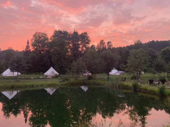 Coucher de soleil flamboyant aux teintes roses et orangées se reflétant dans l'étang d'un domaine de glamping à vendre près de Mont-Tremblant.